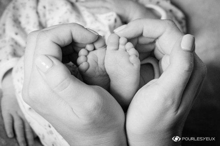 Petits pieds de nouveau né dans les mains de maman - En noir et blanc