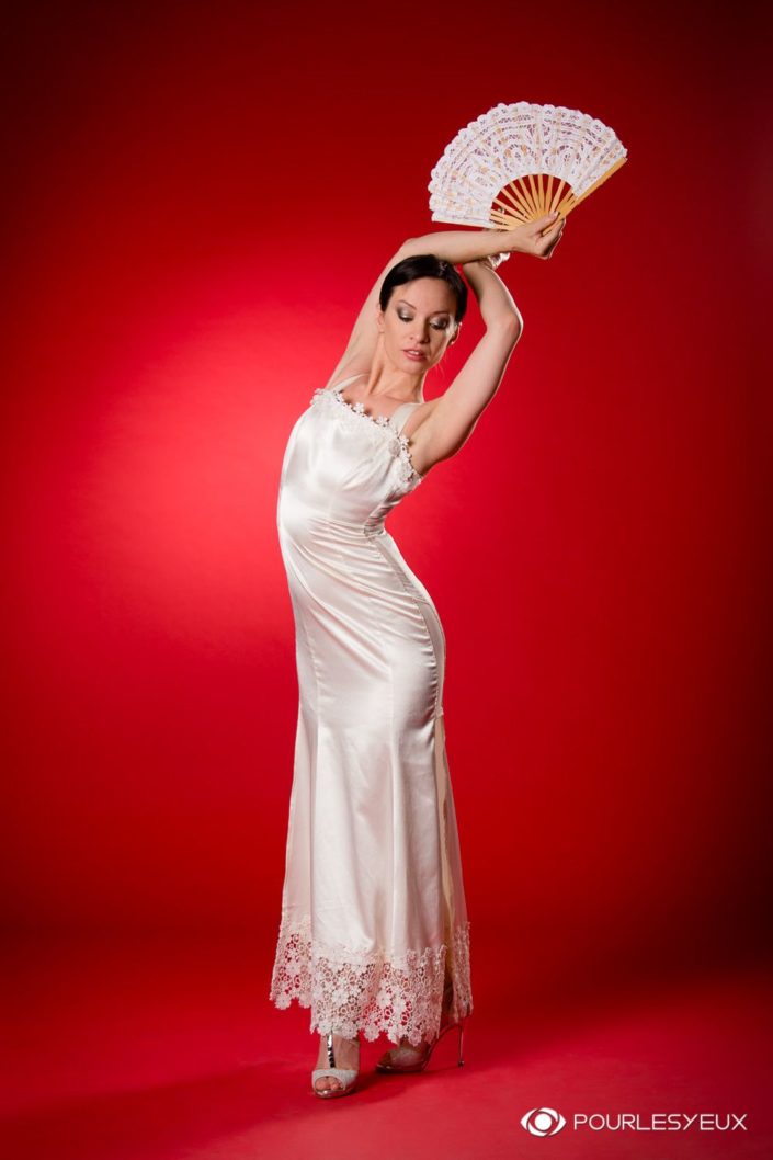 Femme dansant le flamenco en robe de mariée sur fond rouge